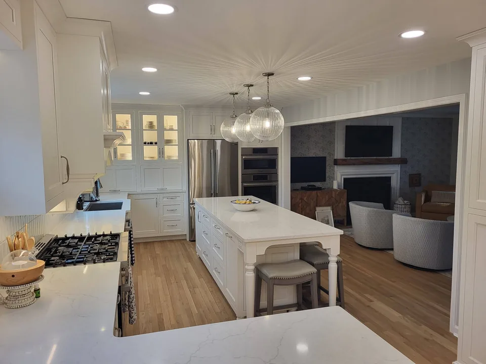 White custom kitchen with lighted glass-front china cabinets, paneled refrigerator surround, and a furniture-style island.