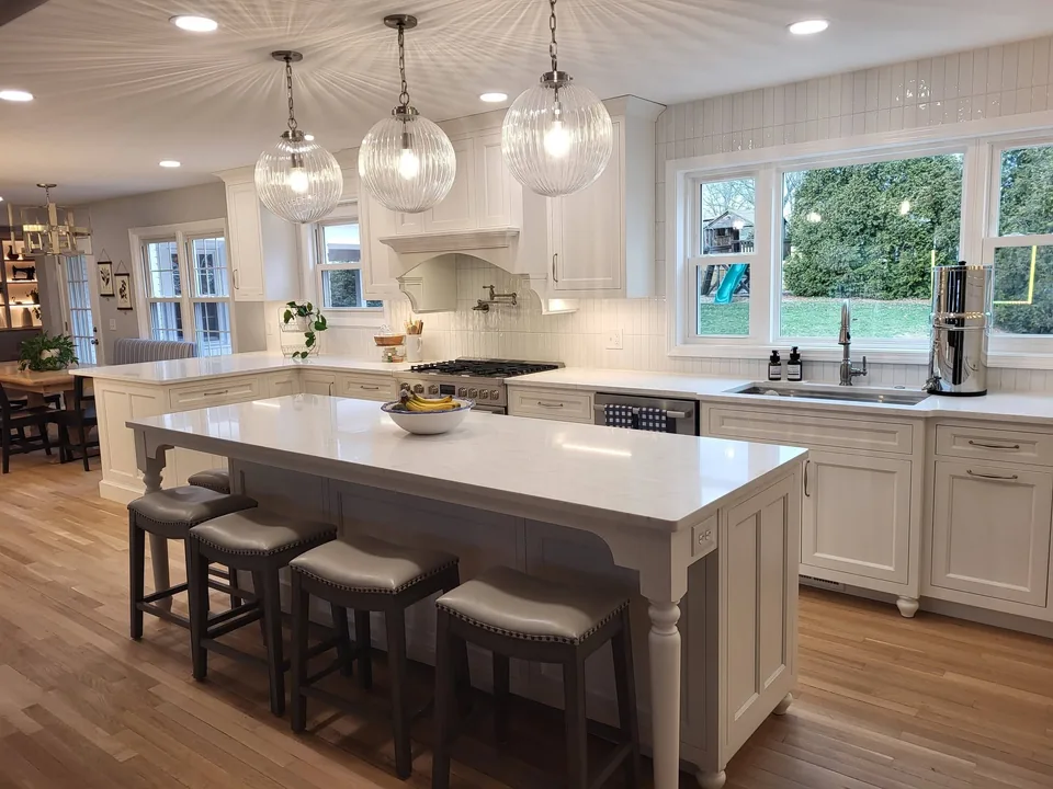 White furniture-style island with turned legs under ribbed glass pendants.