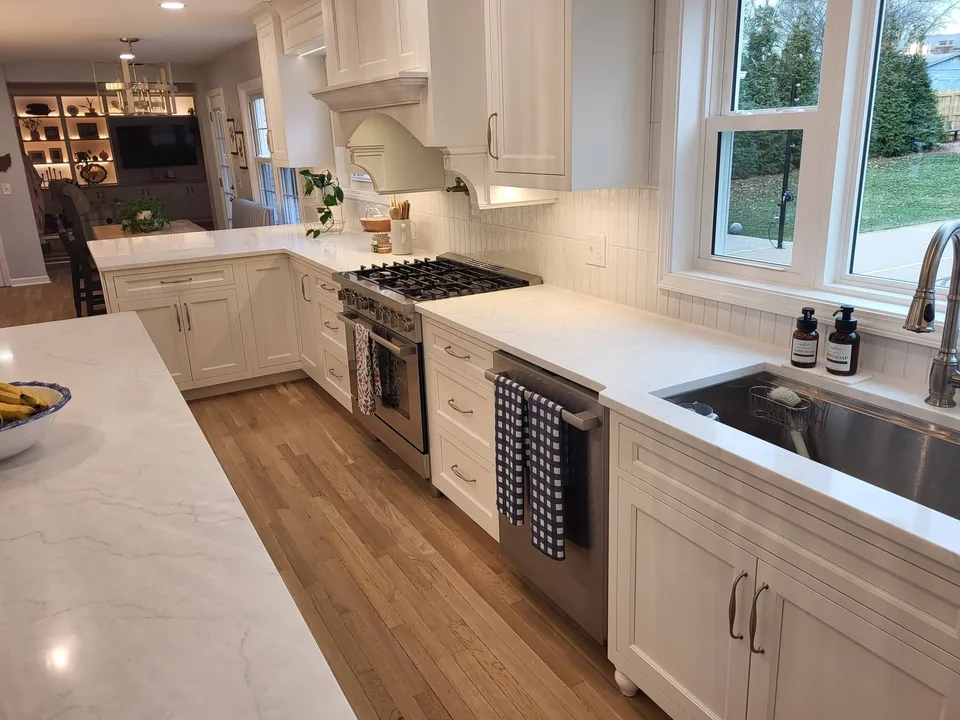 Traditional white painted kitchen with an arched range-hood mantel, farmhouse-style sink base with bun feet, and beadboard detailing.