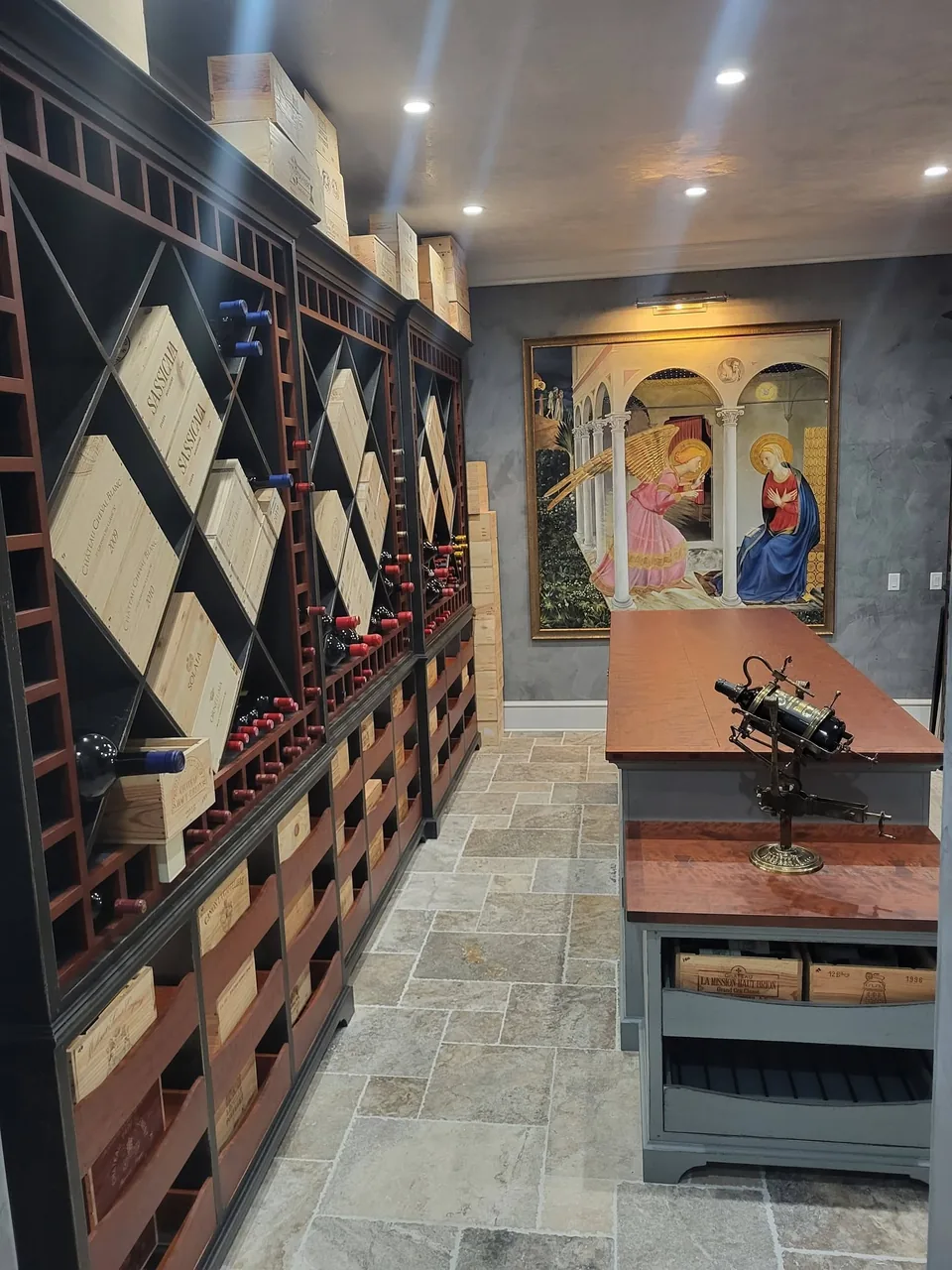 Wine cellar with floor-to-ceiling two-tone racking: dark painted cases with warm-toned wood diamond bins and crate drawers.